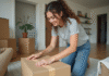 Argent pour déménager : astuces et conseils pour réussir son déménagement Jeune femme emballant des cartons dans un salon moderne